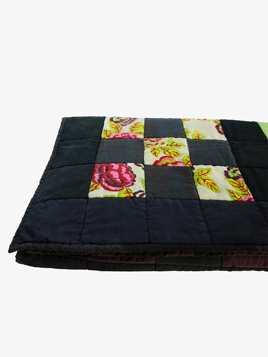 Folded view of Lily Raskind patchwork quilt displaying quilt thickness and floral square detail.
